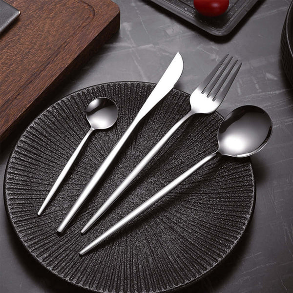 Stainless steel cutlery set displayed on a black textured plate featuring spoon, fork, knife, and teaspoon.
